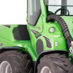 Close-up view of the Avant 845 GT mini loader, focusing on the hydraulic hoses and part of the enclosed cabin. The green loader showcases rugged tires and detailing, emphasizing its robust design for heavy-duty tasks.